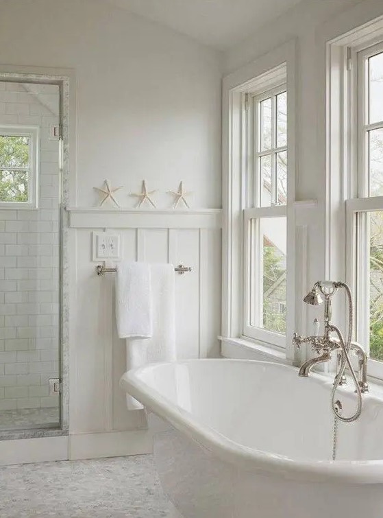 a neutral bathroom with a coastal feel, double-hung windows, an oval abthtub, a shower space and neutral towels