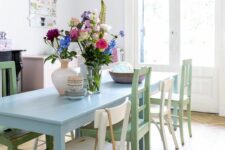 a pastel dining room with a blush sideboard, a blue table, green chairs and a blue pendant lamp is a stylish and cool space