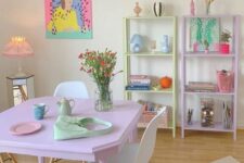 a pastel dining room with matching pastel storage units, a pink dining table and white chairs, a colorful rug and artwork