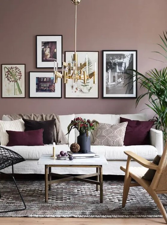 a refined living room with mauve walls, a creamy sofa, a bright gallery wall and mismatching chairs