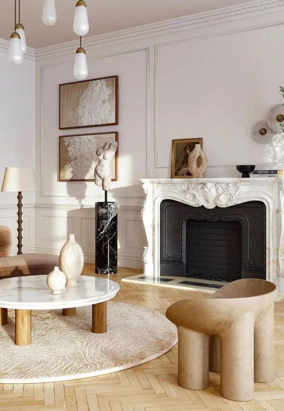 a refined neutral living room with a French fireplace, warm-colored seating furniture, a low coffee table and some art
