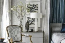 a relaxing grey and blue bedroom with printed wallpaper, a bed with a canopy, an antique printed chair and a gallery wall
