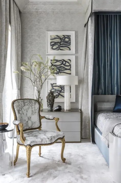 a relaxing grey and blue bedroom with printed wallpaper, a bed with a canopy, an antique printed chair and a gallery wall