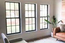 a series of black frame double-hung windows gives a lot of light and contrasts the neutral space with its black framing