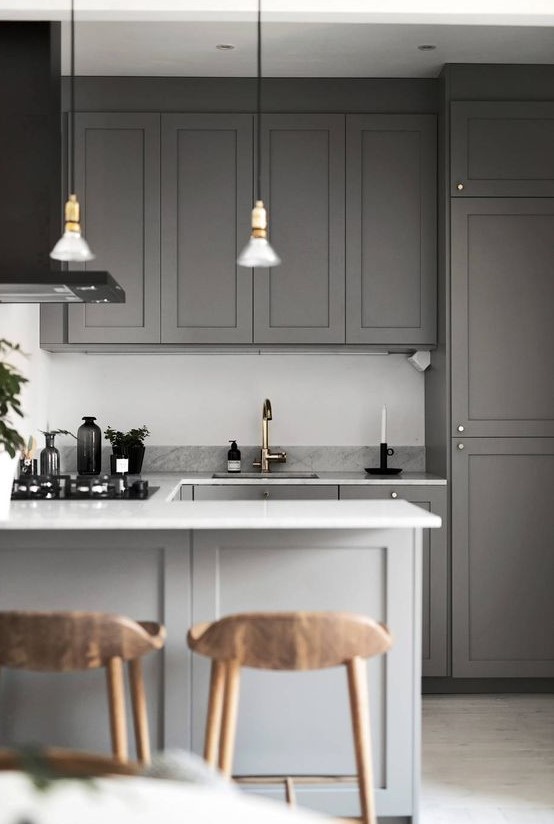 a simple contemporary space done in grey, with a white backsplash, stone countertops and metallic touches
