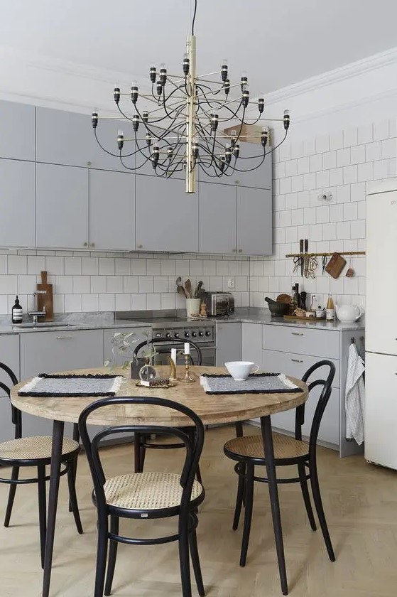 a simple modern light grey kitchen is spruced up with a gorgeous chandelier and a stylish dining set with black touches