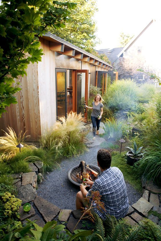 a small garden space with greenery and shrubs, with outdoor lamps and a small fire bowl is a cozy and lovely space