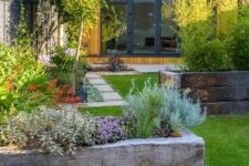 a small modern garden with lawns, garden beds with greenery and blooms and some shrubs is a lovely space