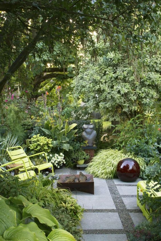 a small modern garden with lots of greenery, blooms, shrubs, a fire bowl, a large ball, neon yellow chairs