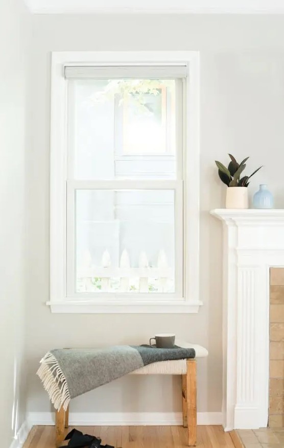 a small nook with a double-hung window, a small stool, a non-working fireplace and some lovely decor