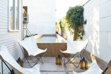 a small outdoor space with a long and narrow pool and four white butterfly chairs plus candle lanterns