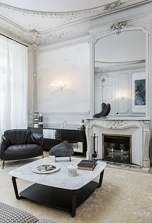 a sophisticated French living room with molding on the ceiling, black leather furniture, a low coffee table, a French fireplace
