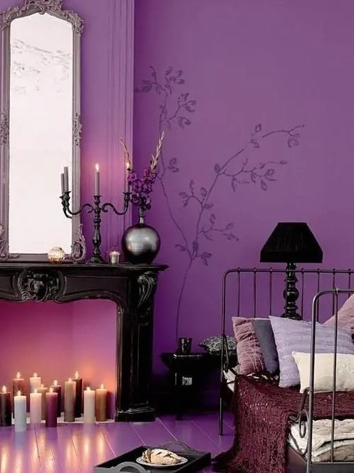 a sophisticated bedroom with a purple accent wall, a non-working fireplace with candles, a vintage metal bed with pillows and elegant decor