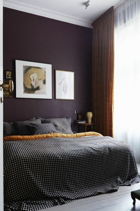 a sophisticated moody bedroom with a deep purple accent wall, mustard and grey textiles and a stylish gallery wall