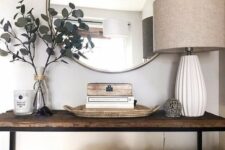 a stained bench as a console table, a floor lamp, some eucalyptus, a round mirror and some books is a cool idea for living room decor