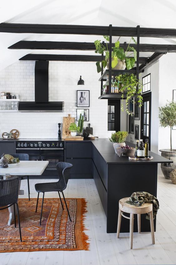 a stylish contemporary black kitchen with flat cabinets, a black hood, black suspended shelves and potted herbs is chic