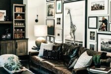 a stylish farmhouse living room with stained furniture, a floor to ceiling gallery wall, a black leather sofa, a black coffee table and a chandelier