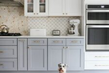 a two-tone kitchen with shaker cabinets, a white scallop backsplash, brass handles and knobs plus a bold rug