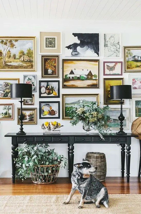 a very chic gallery wall with gilded frames and various types of paintings will blow your mind away