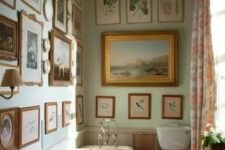 a vintage bathroom with light green walls, a gallery wall that covers two walls at once, a clawfoot bathtub and a free-standing sink