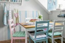 a vintage-inspired pastel dining room with blue and white paneling, a vintage table and pastel chairs, blue shutters and a curtain plus pastel towels