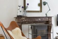 a vintage-inspired space with a faux fireplace, a large mirror in an ornated frame, a hearth, an amber leather butterfly chair