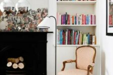an eclectic living room with a black non-working fireplace, built-in bookshelves, a series of mirrors and an antique chair redone with polka dot upholstery
