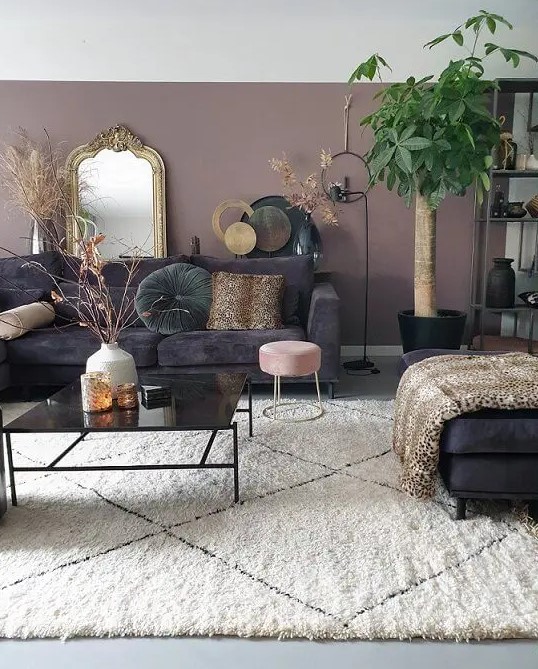 an eclectic living room with mauve walls, dark furniture, potted plants and grasses plus a mirror in a vintage gold frame