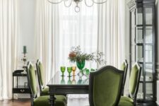 an exquisite dining room with a black glass buffet, a vintage black table, green antique chairs and a cool chandelier