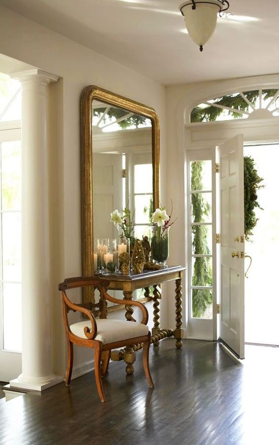 an exquisite entryway with an oversized mirror, a vintage console table, an antique chair is a stylish and chic space