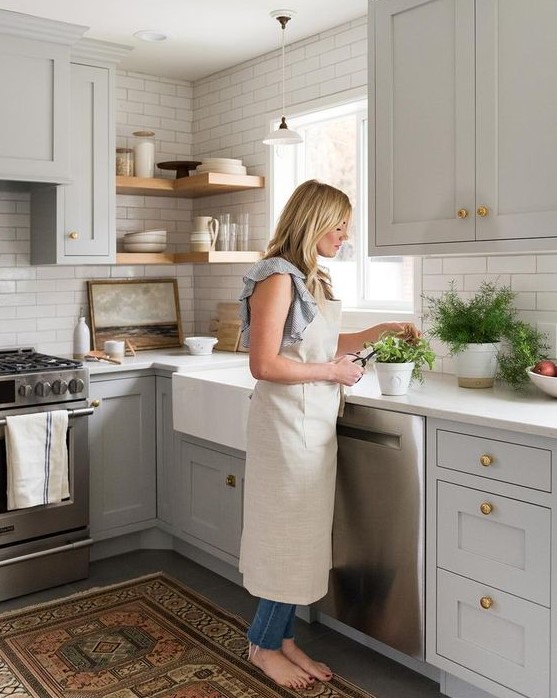 dove grey cabinets, a white tile backsplash and white countertops, wooden shelves and a boho rug for a chic look