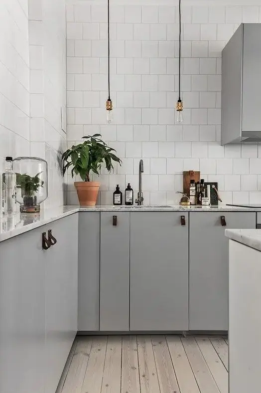 dove grey cabinets, white tiles that cover the whole walls and industrial pendant lamps for a stylish Scandinavian space