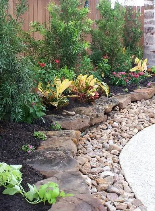 a large pebble and rough rock garden border brings much texture and a rough touch to the elegant outdoor space