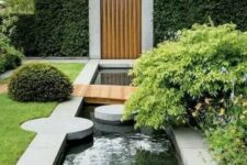 04 a modern garden with lots of greenery and bushes, with a water feature, stone pavements and a pathway over the water feature