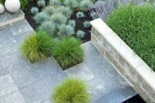 06 a modern outdoor space with lots of grasses and plants, with stone pavemets and a small water feature with a large rock