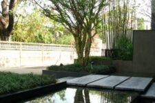 10 a modern pond with a stone path over it, with greenery around and some trees compose a relaxed and cool space