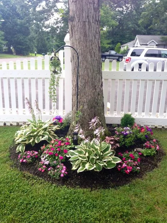 a tree surrounded with bold blooms and catchy greenery, with an additional planter on the hook is amazing