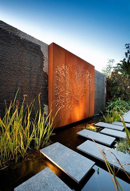 a modern pond with tiles over the water, with water plants and an orange metal wall with detailing are a bold and chic combo