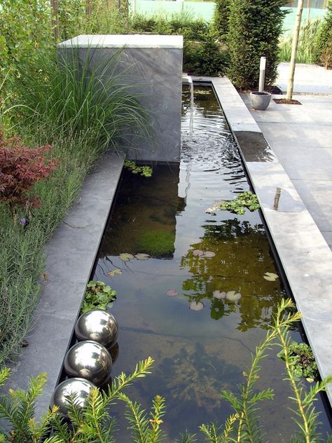 a modern pond with water plants, metal balls for decor and a waterfall will make your outdoor space cool and catchy