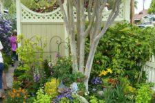 14 a tree with a garden bed with greenery and bright flowers right around it is a super cool idea for a bold garden
