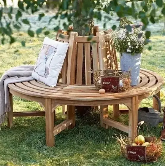 a classic wooden wrap around bench for a tree, with blankets, pillows and wire baskets is a lovely rustic decor idea