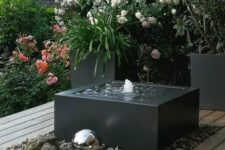 18 a modern interpretation of a fountain, with a black bow, pebbles around and some silver spheres next to it is a cool idea
