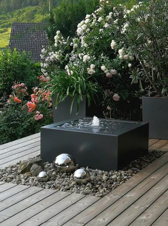 a modern interpretation of a fountain, with a black bow, pebbles around and some silver spheres next to it is a cool idea