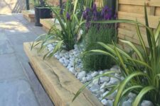 21 a wooden garden bed edge, bright flowers and greenery all covered with neutral pebbles on top