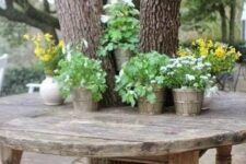 22 a potting bench around the tree, with lots of potted greenery and blooms is a lovely idea for your garden, a fresh space for gardening