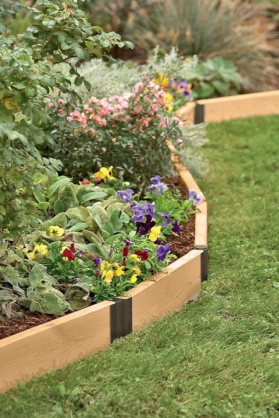 pivoting wooden garden bed edging in a light shade contrasts the bright blooms growing