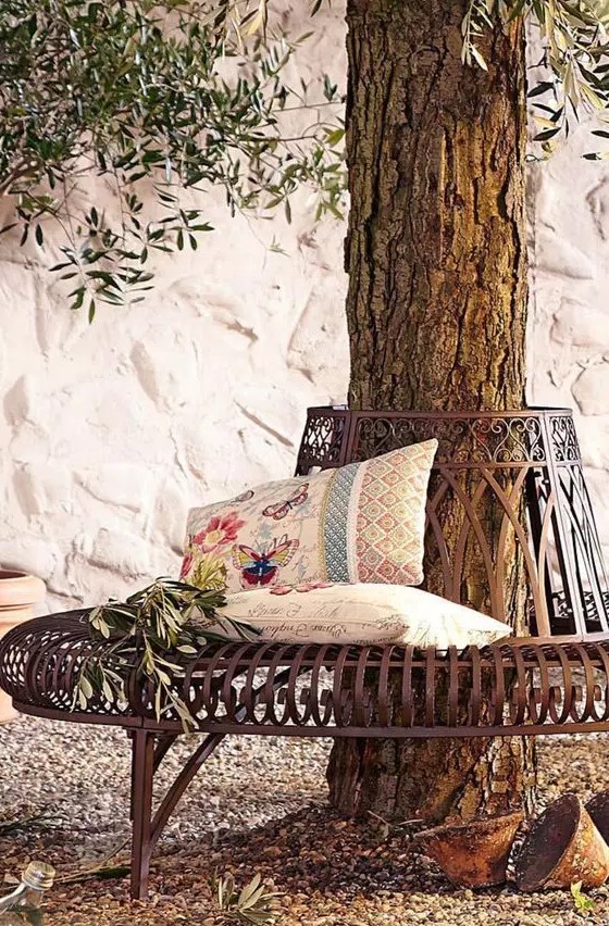 a sophisticated and chic metal bench around the tree, with printed pillows and greenery is a lovely item to sit on