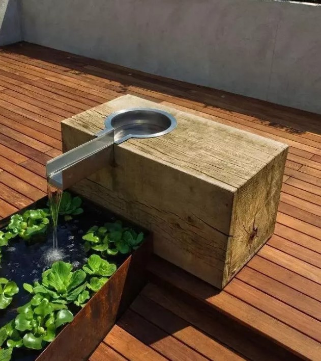 a Corten steel water feature built into a wooden deck is design to develop patina over time and look a bit more vintage