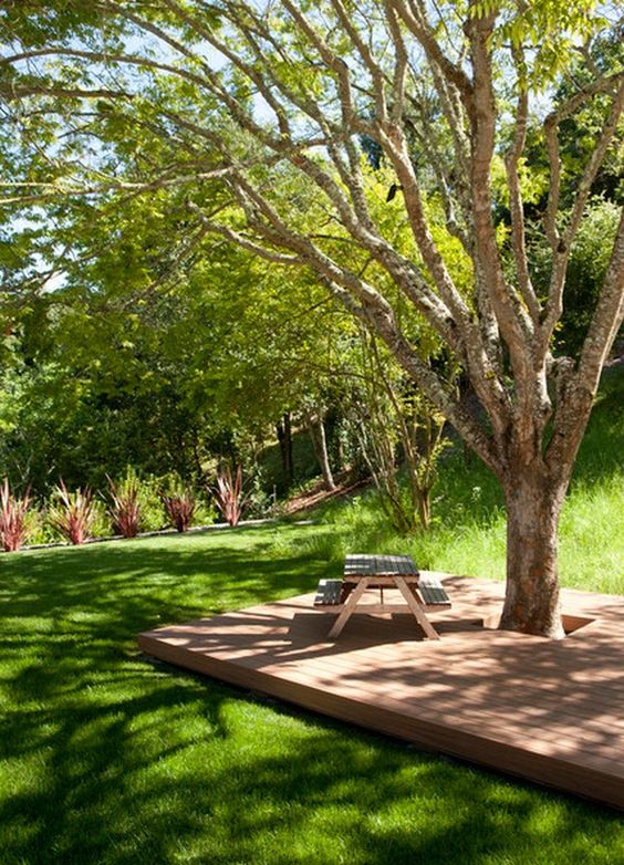 a tree surrounded with a wooden deck, with a table and benches is a simple way to style around the tree and leave it in its place