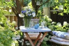 39 a lawn around the tree used as a little dining space, with stained folding furniture, cushions and pillows, hanging candle lanterns and blooms